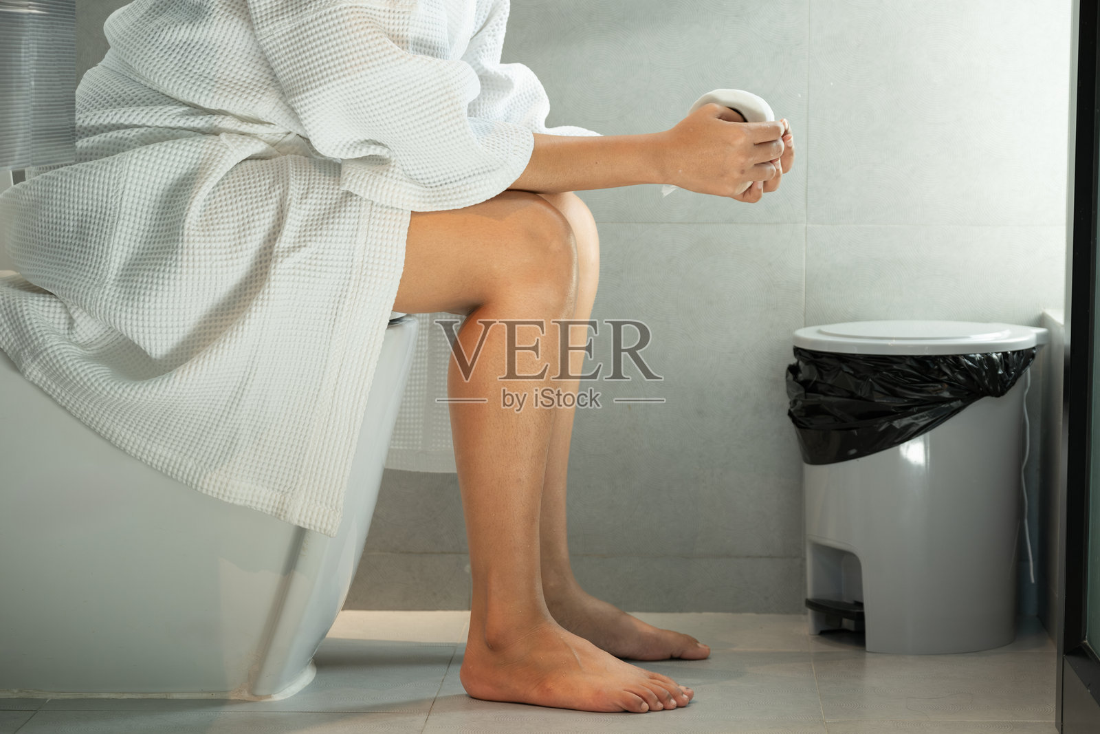 女人坐在卫生间的马桶上，他胃痛，消化系统不好。便秘。腹泻。食物中毒。健康和医药。女人坐在卫生间的马桶上，他胃痛，消化系统不好。Constipat照片摄影图片