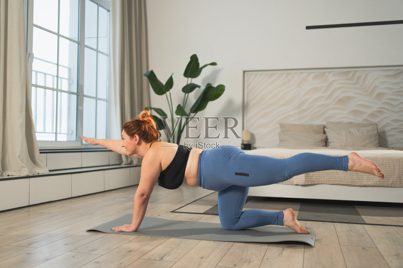 瑜伽健身锻炼训练。在家练瑜伽的女人。加码女性在室内瑜伽垫上做运动。穿着运动服的女孩正在进行减肥训练。运动和健身。照片摄影图片