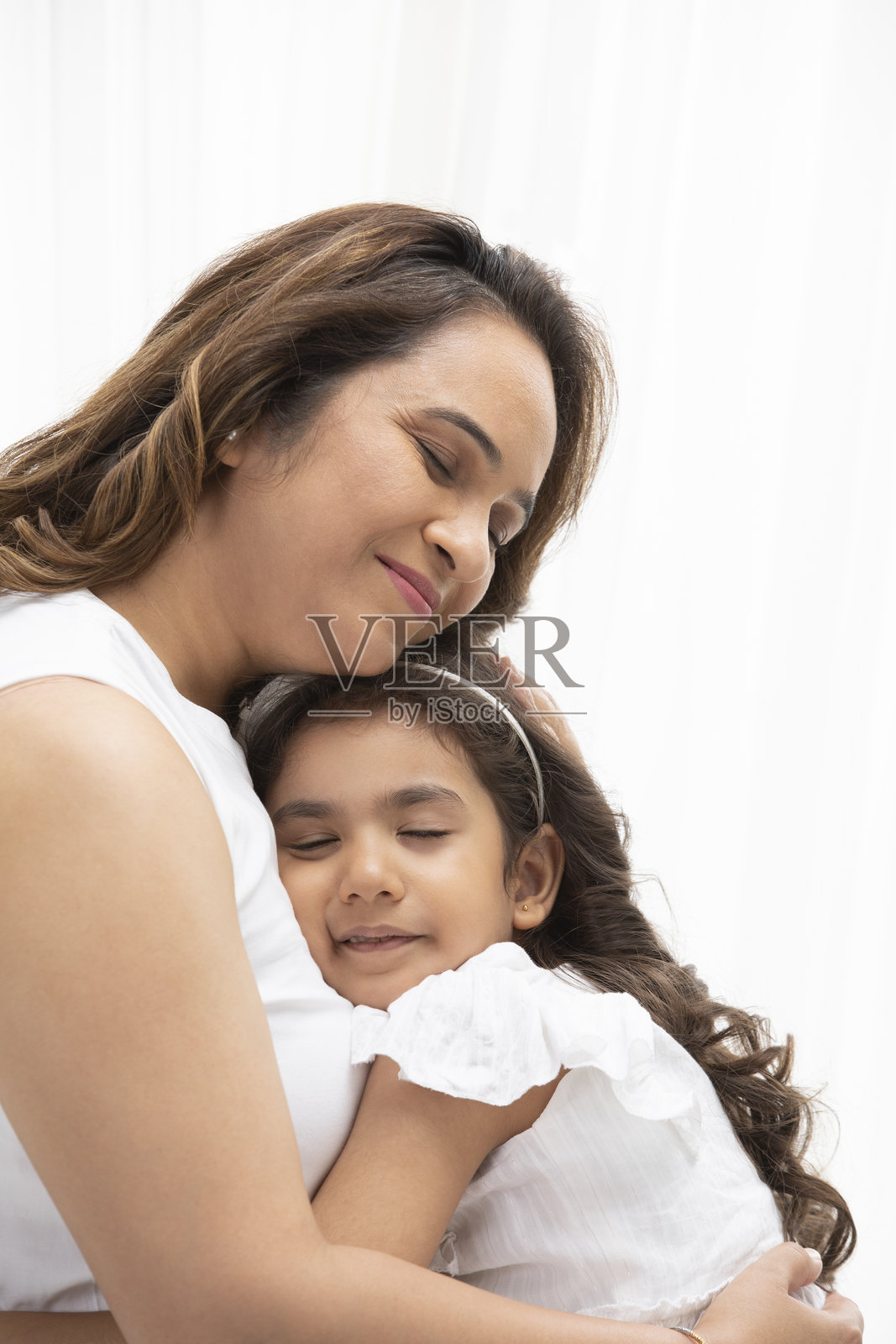 母亲和女儿在白色背景上单独拥抱。照片摄影图片