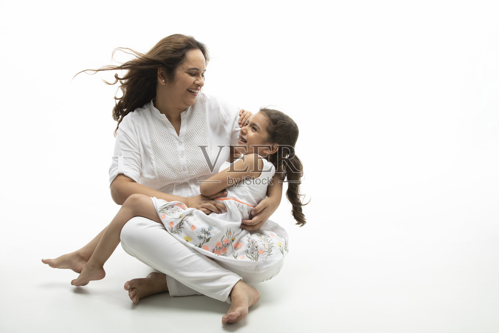 微笑的妈妈和女儿拥抱，隔离在白色背景。照片摄影图片