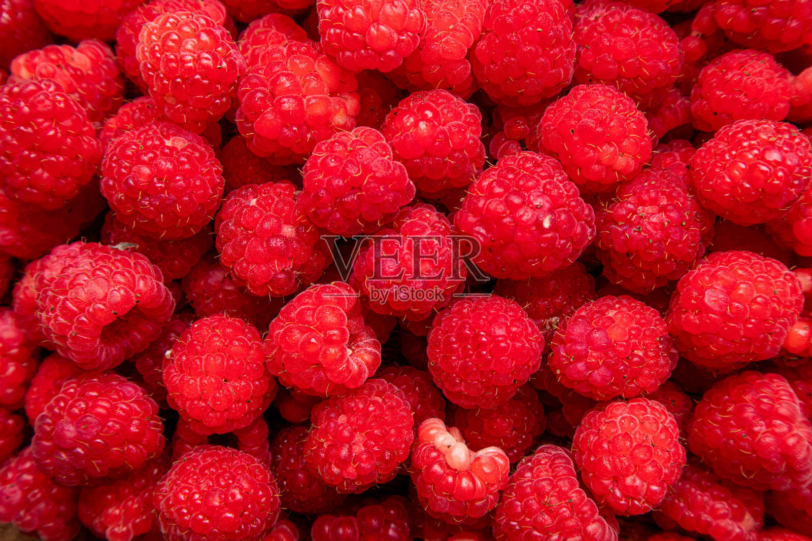 桌上有各种各样的覆盆子。覆盆子是可食用的，有酸甜两种口味。它们还富含维生素C，对身体有益。照片摄影图片