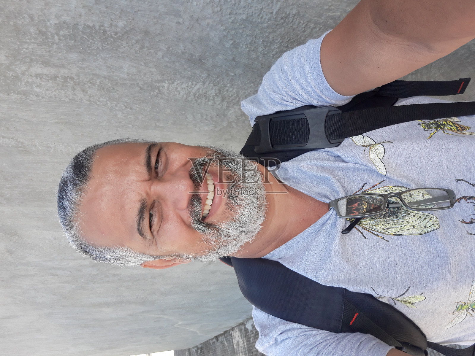 背着背包站在墙上自拍的男人的肖像照片摄影图片