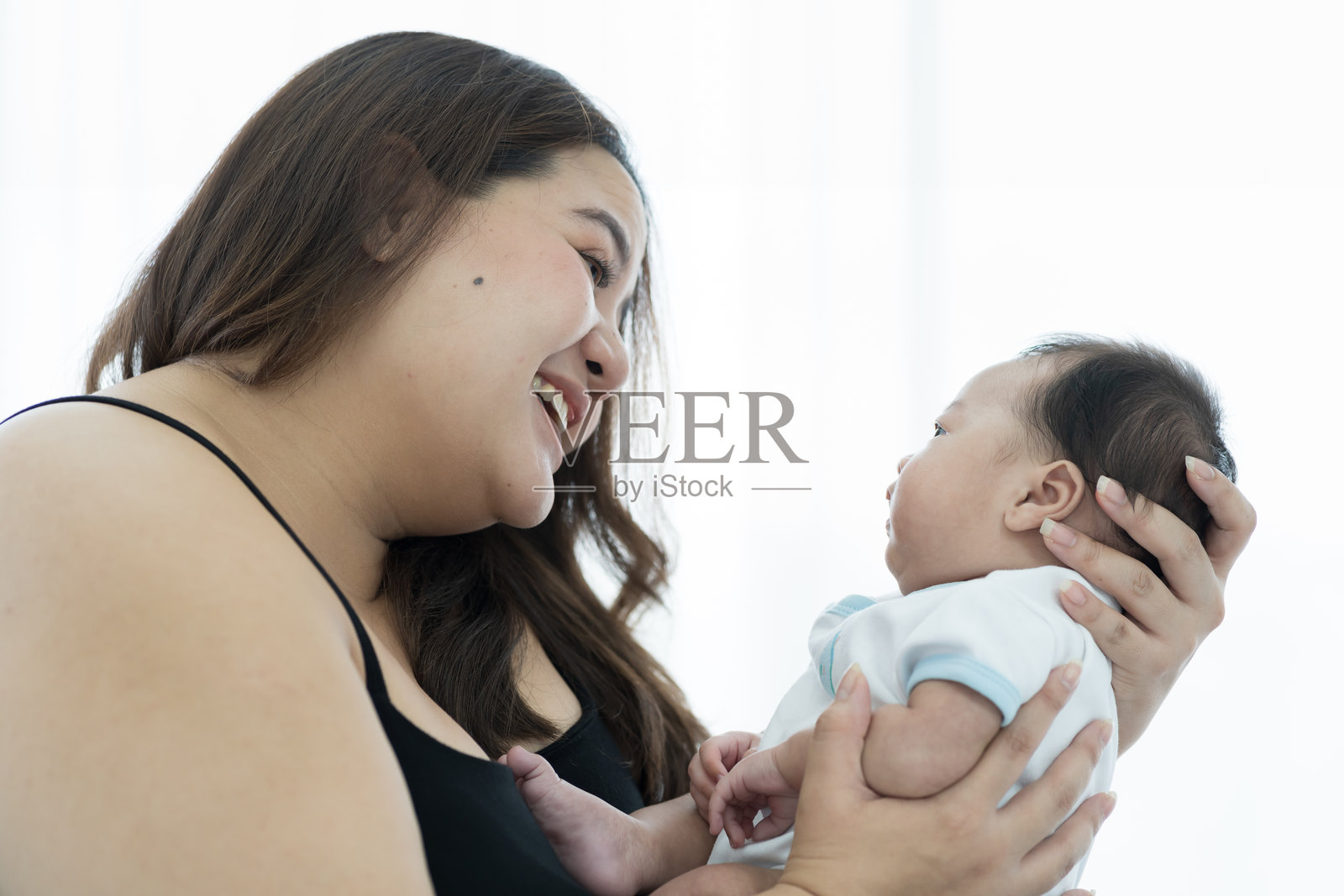 亚洲大码妈妈在家里抱着她刚出生的孩子照片摄影图片