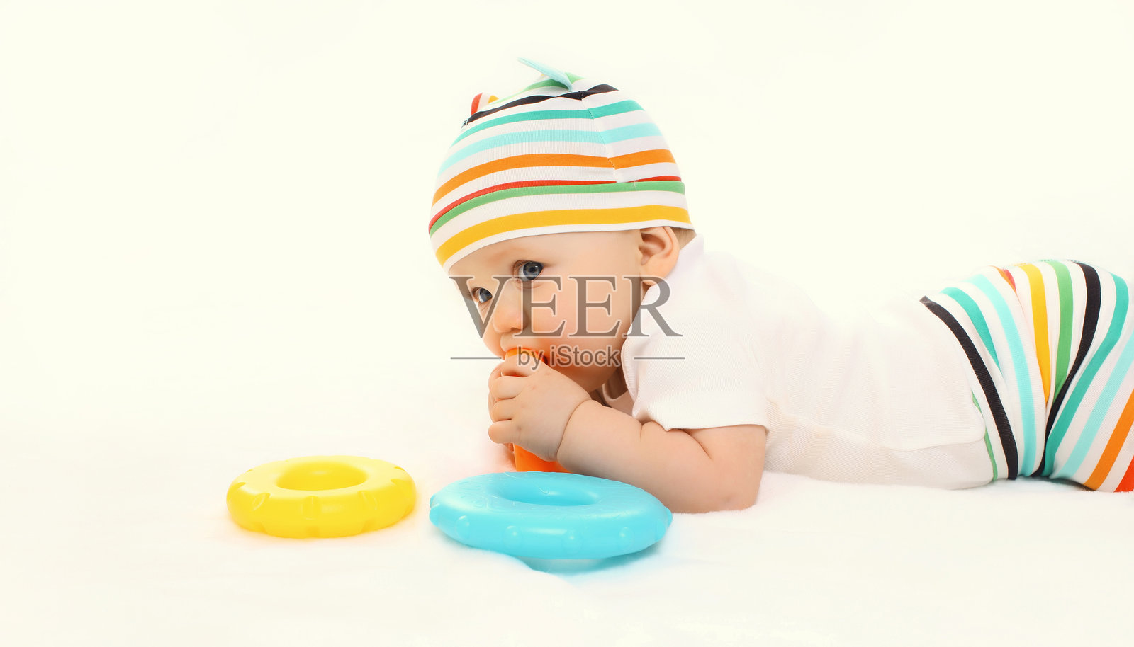 快乐的小婴儿坐在白色工作室背景的地板上玩玩具照片摄影图片