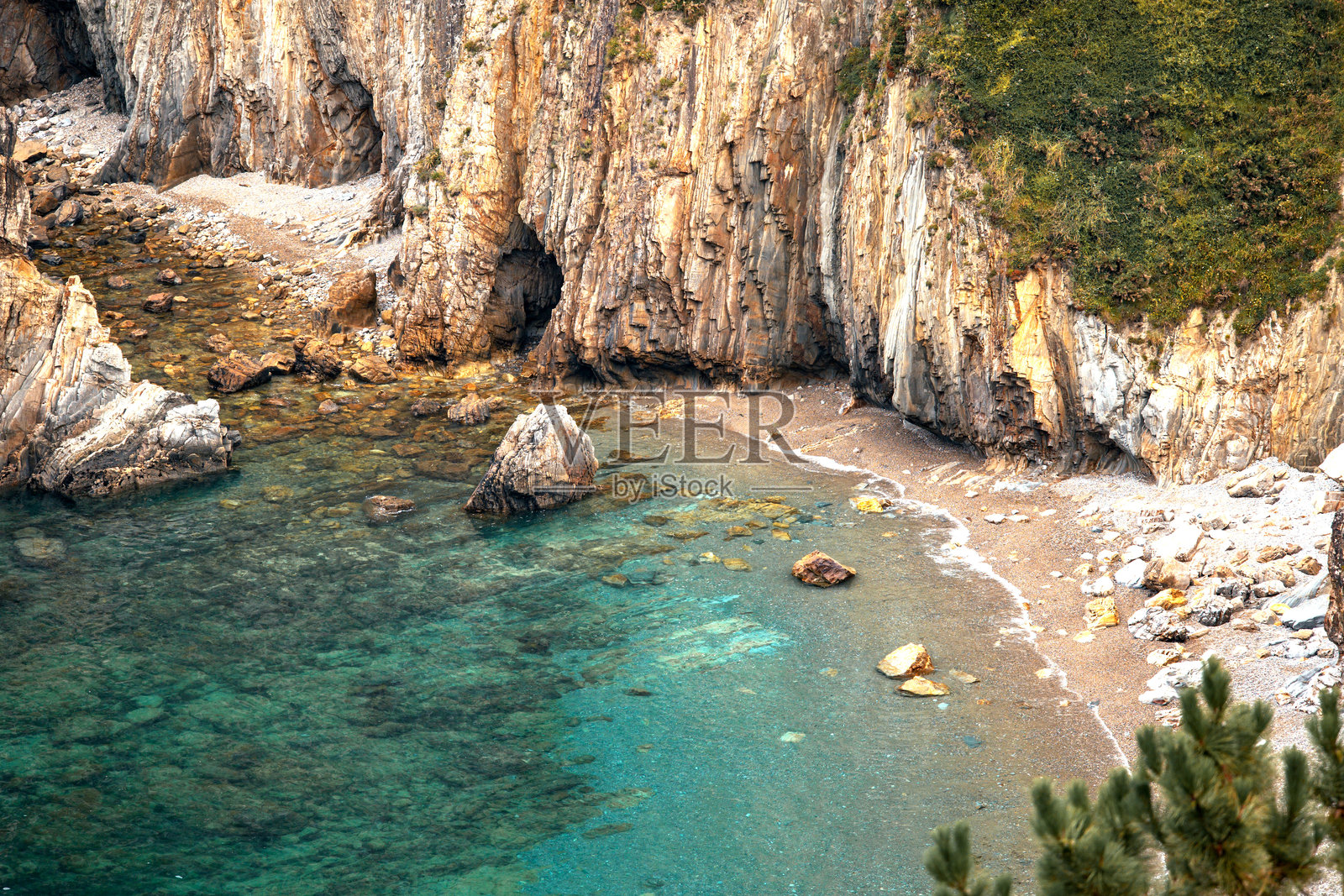 幽静的海滩，清澈的海水和岩石悬崖照片摄影图片