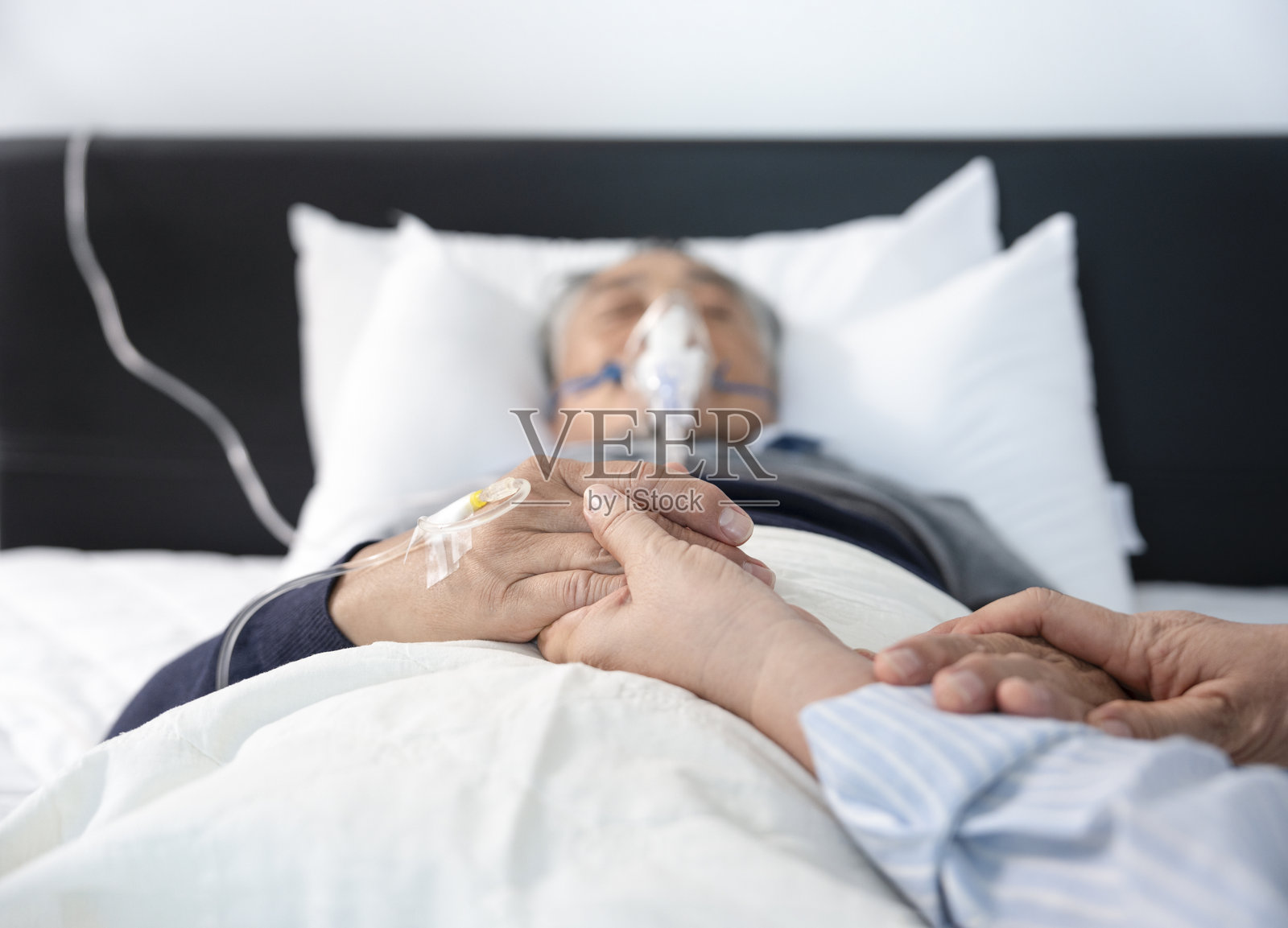 妻子握着正在吸氧和输液的绝望老年男病人手的场景照片摄影图片