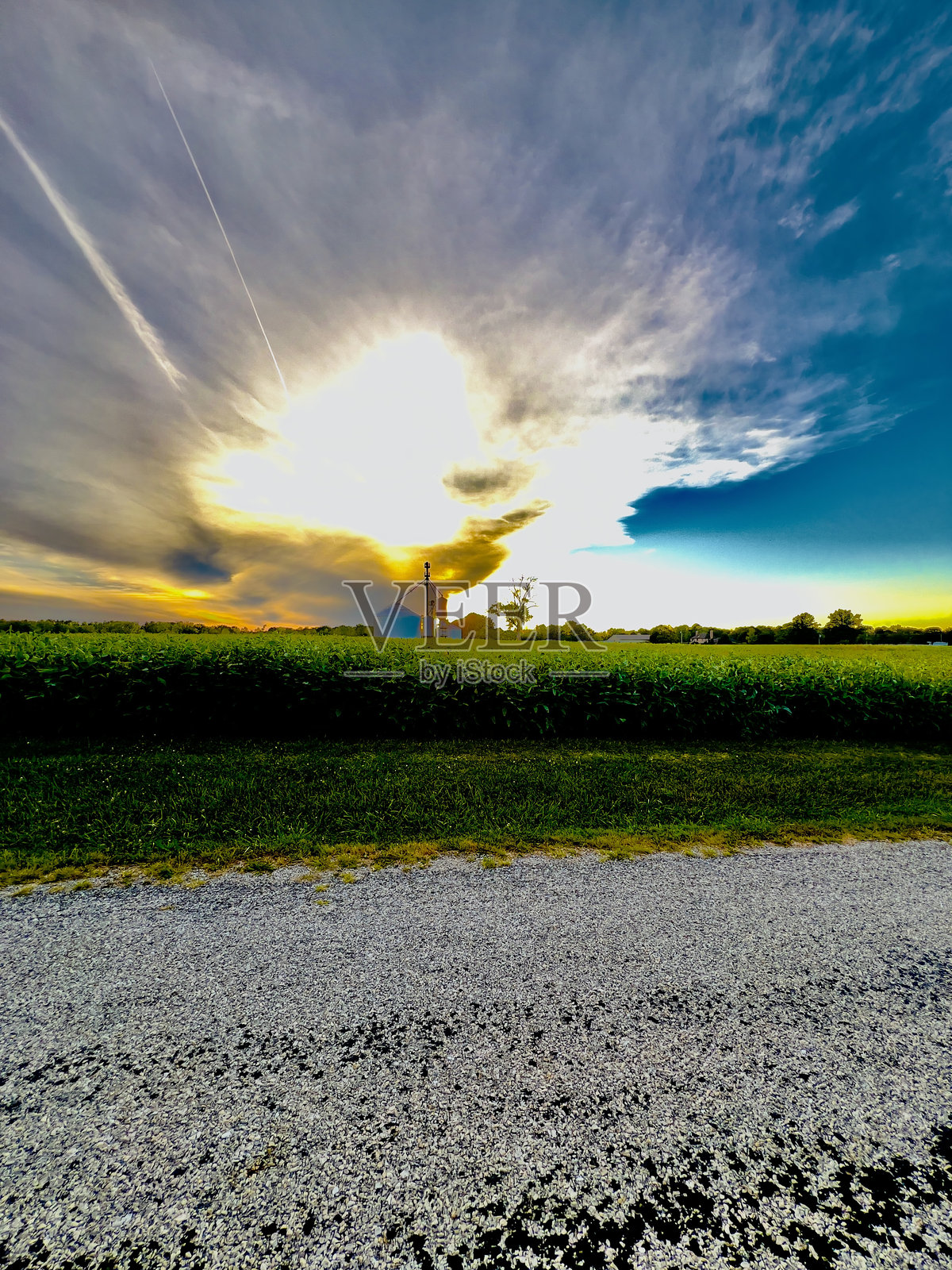 筒仓在夕阳下的田野与云和蓝色，黄色的天空。照片摄影图片