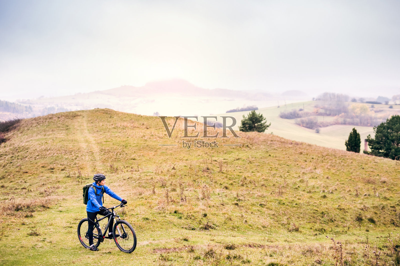 活跃的男子骑着自行车在美丽的大自然中间，初秋的早晨。健康生活方式的概念。照片摄影图片