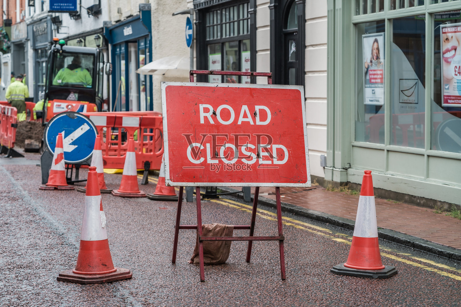 道路封闭标志，背景中有交通锥和建筑障碍物挡住了街道照片摄影图片