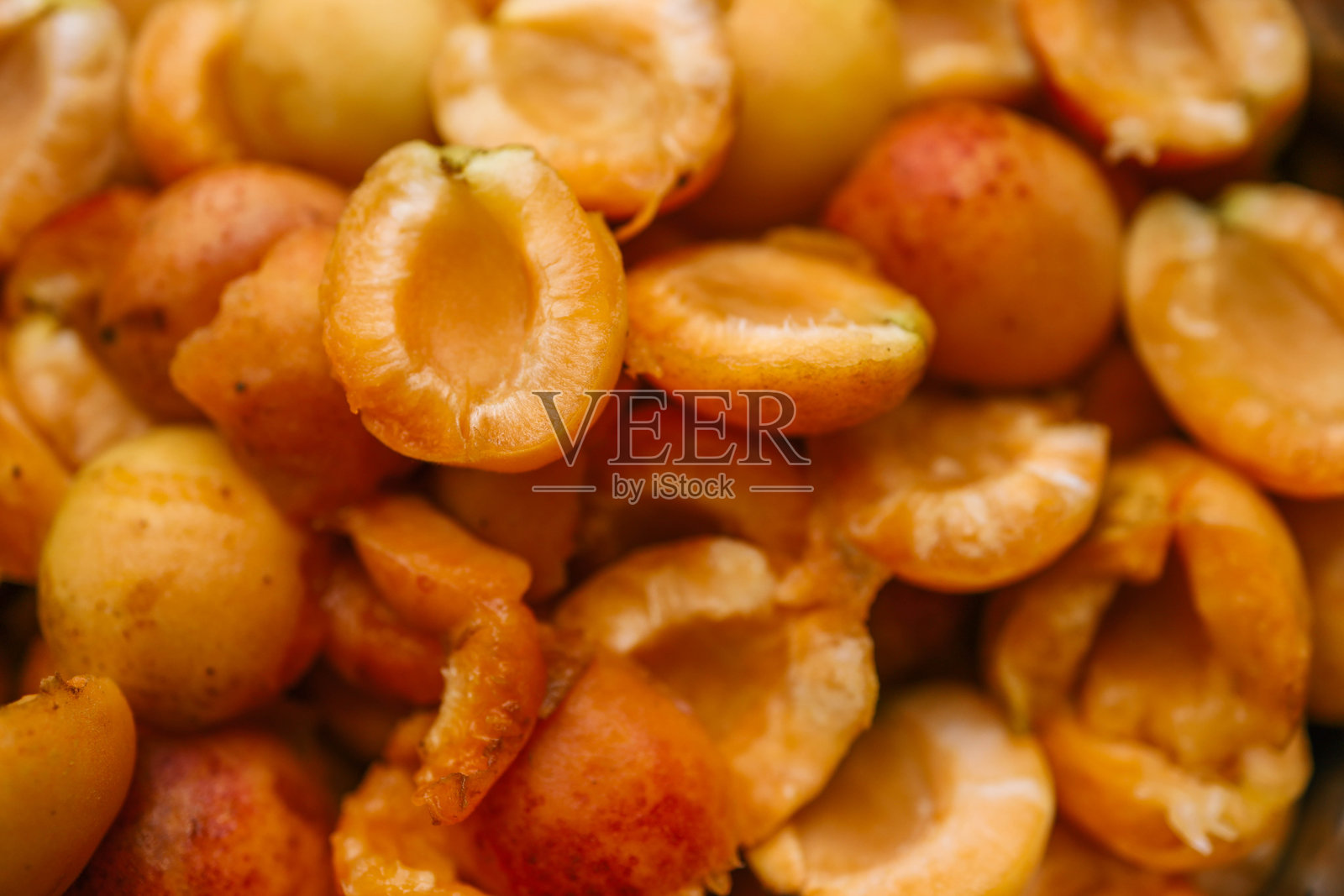 对半切开的杏子特写，展示其鲜艳的橙色和多汁的质地。新鲜水果看起来美味而成熟，强调自然之美和成熟度照片摄影图片