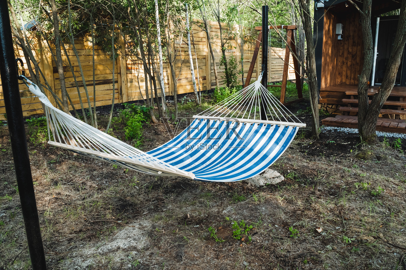 院子里挂着一张蓝白条纹的吊床，在宁静的自然景观中，绿草如茵，为您提供一个宁静的放松场所照片摄影图片