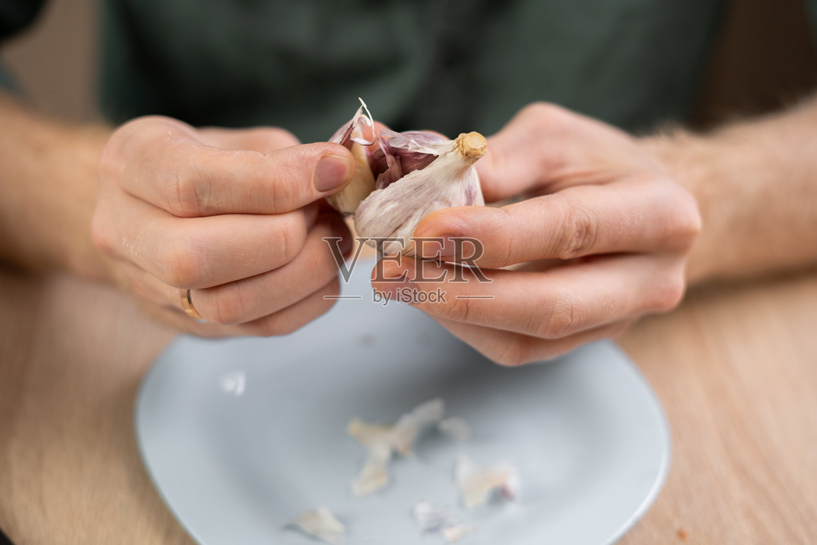 烹饪和家的概念。男性用手剥盘子上的大蒜的特写照片摄影图片