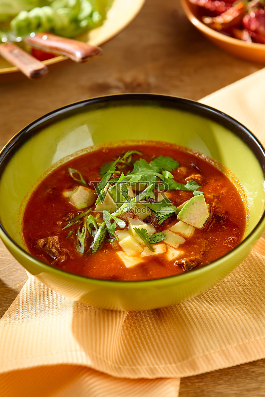 鲜艳的红色汤与新鲜的装饰在明亮的绿色碗在轻木桌子-高对比度的食物摄影照片摄影图片