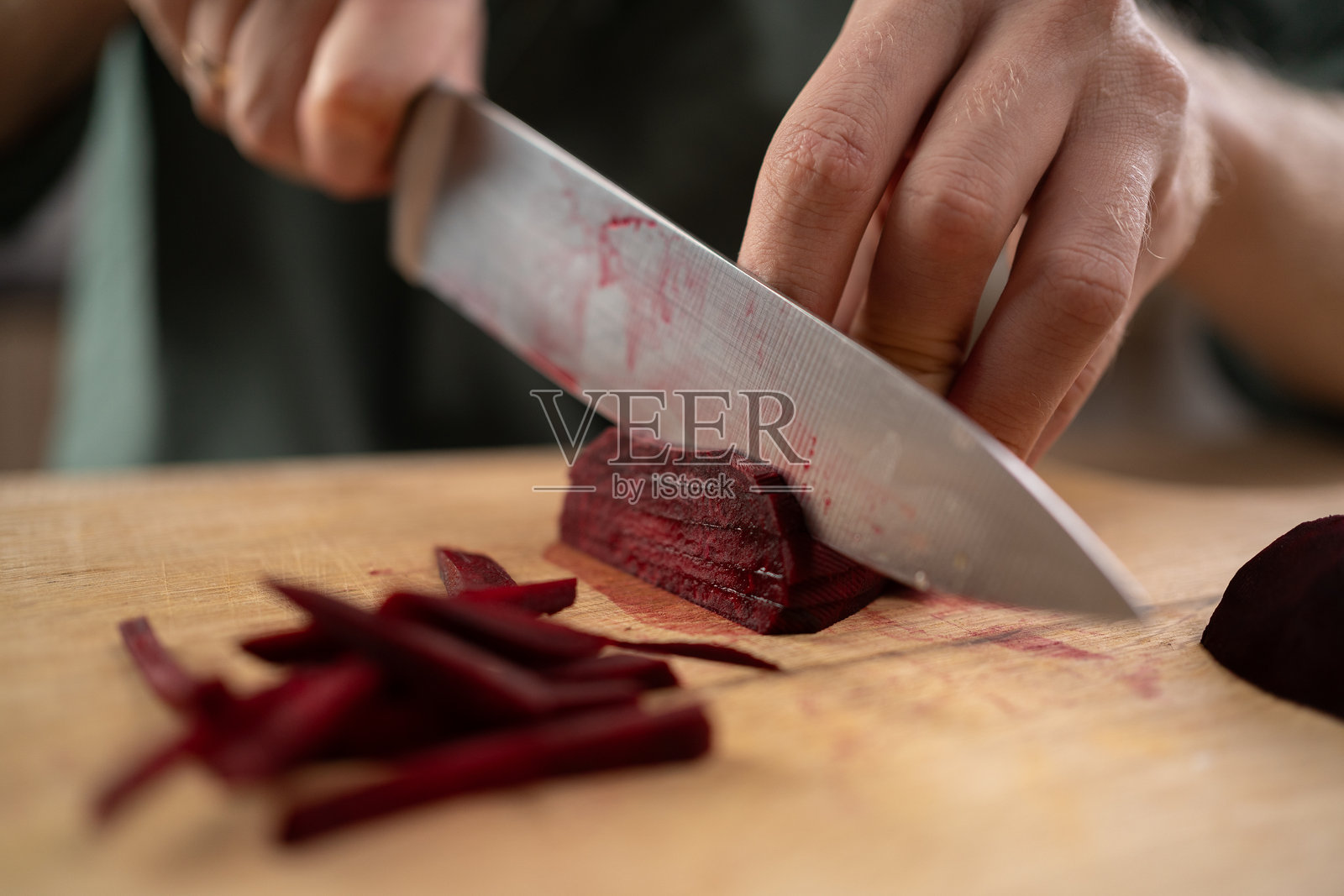 一个人的手在木板上把甜菜根切成条，在家里准备罗宋汤照片摄影图片