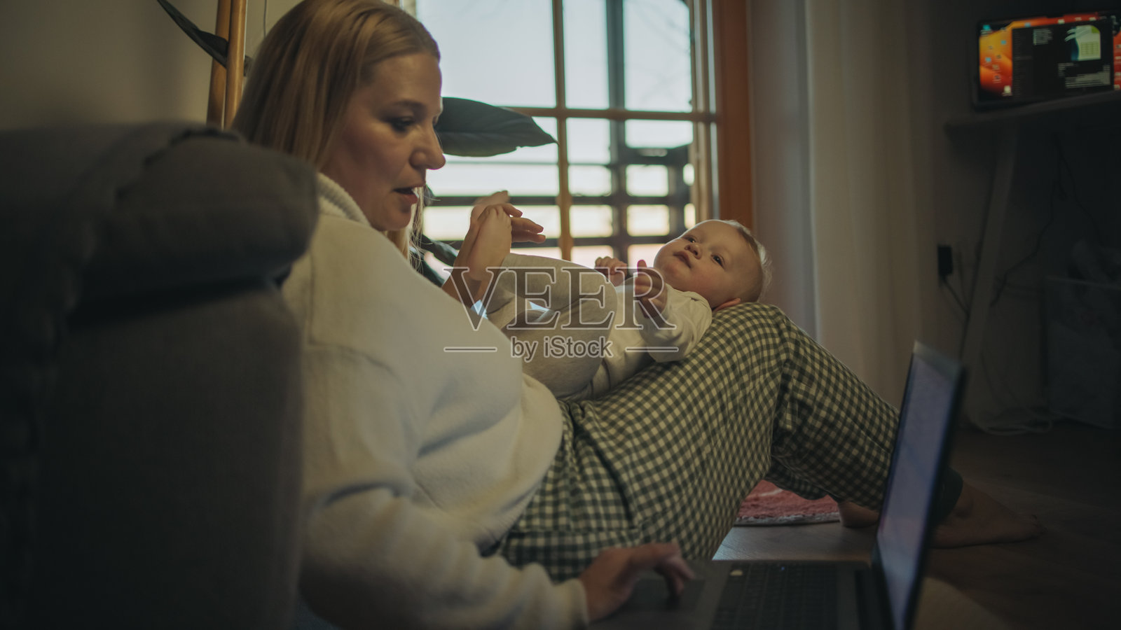 多任务处理的白人母亲带着孩子进行远程工作照片摄影图片