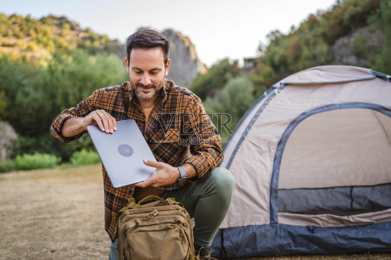 成年男子跪下来，把笔记本电脑装进背包，准备回家照片摄影图片