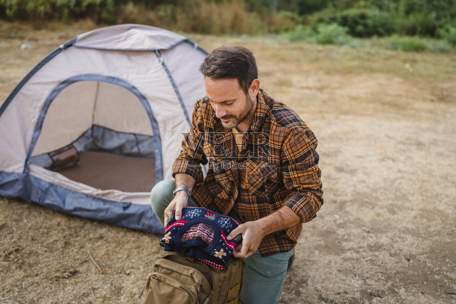 一个成年男子跪下来，收拾好他的毛衣背包，准备回家照片摄影图片