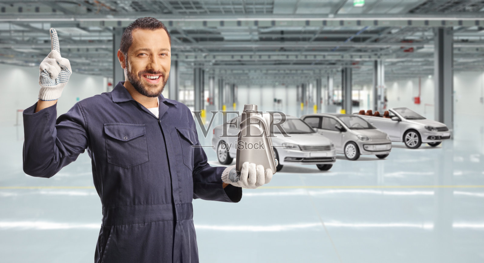 汽车修理工拿着一个发动机油塑料瓶，指着上面的车库照片摄影图片