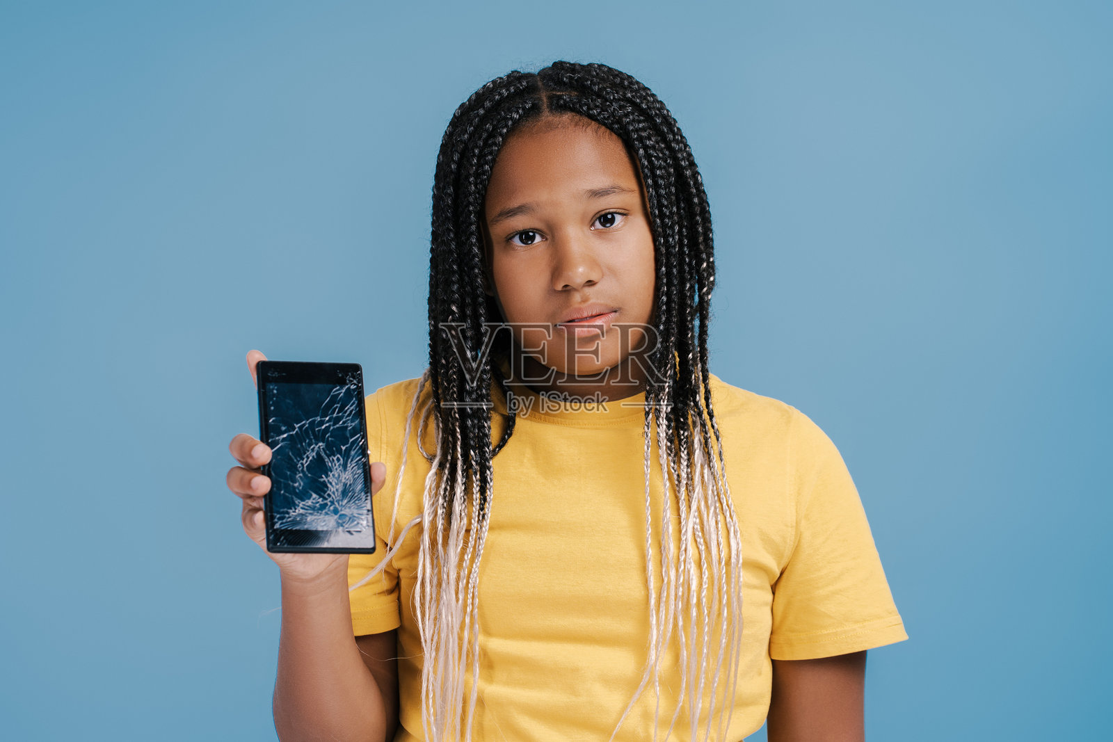 小女孩拿着一个坏了屏幕的智能手机，看起来很担心照片摄影图片