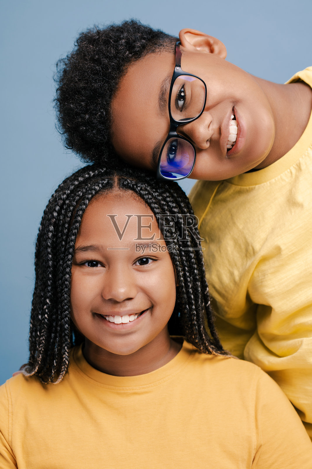 垂直照片，微笑的非洲裔美国孩子粘在一起看着相机孤立的蓝色照片摄影图片