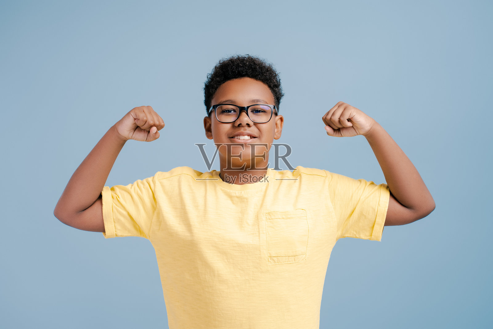 一个身穿黄色t恤的强壮非洲少年，露出肌肉和二头肌照片摄影图片