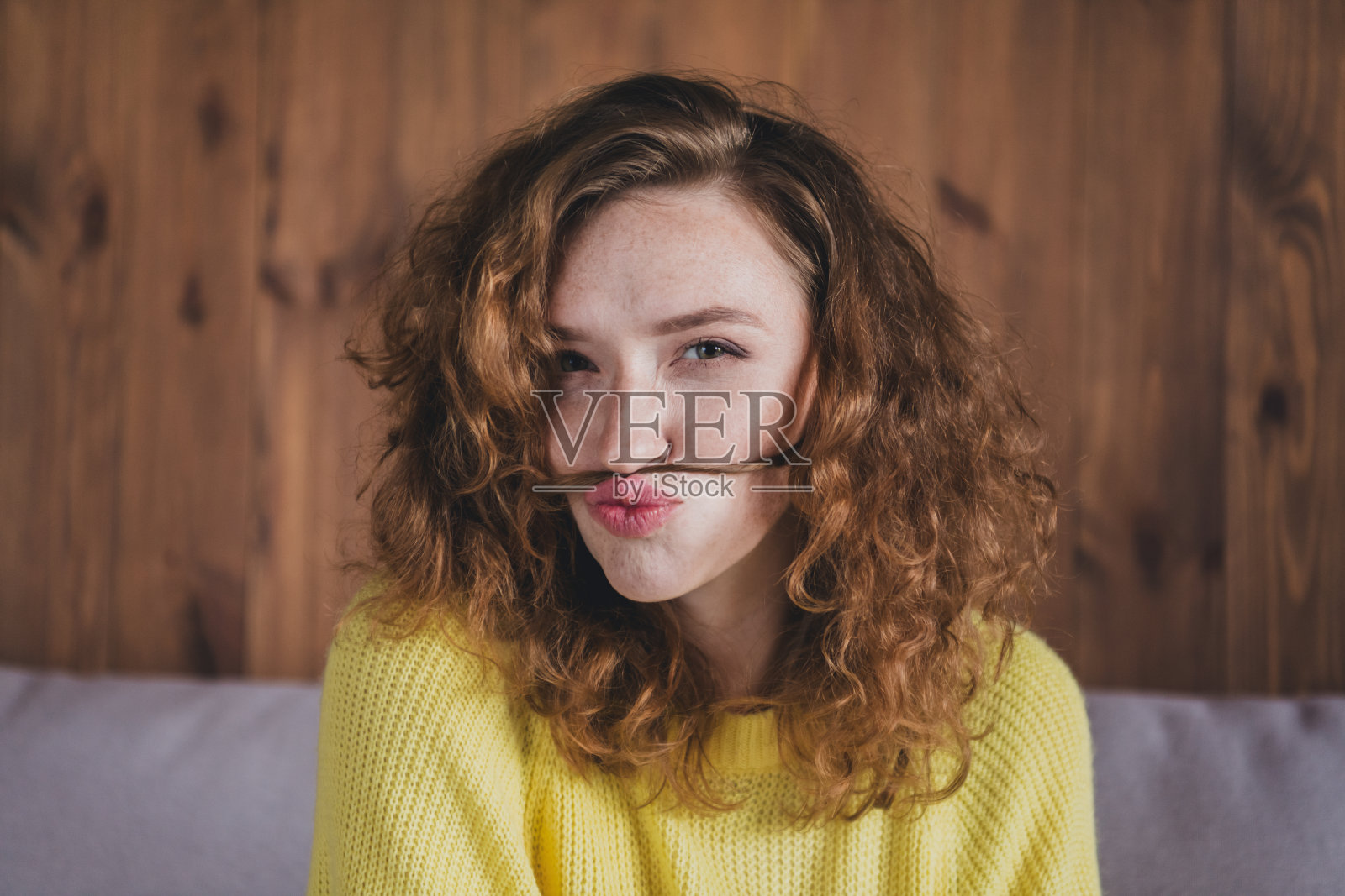 迷人的年轻女性假胡子的照片愚弄穿着黄色毛衣舒适的日光家室内客厅照片摄影图片