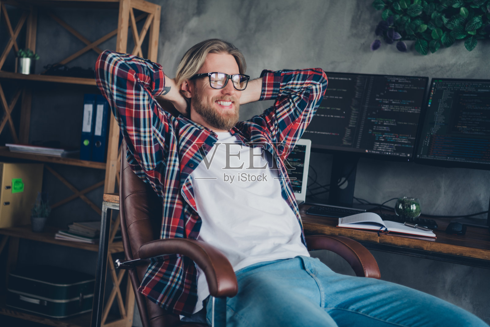 照片开朗自信英俊大胡子程序员年轻人坐在扶手椅工作场所与电脑显示器在室内游戏室照片摄影图片