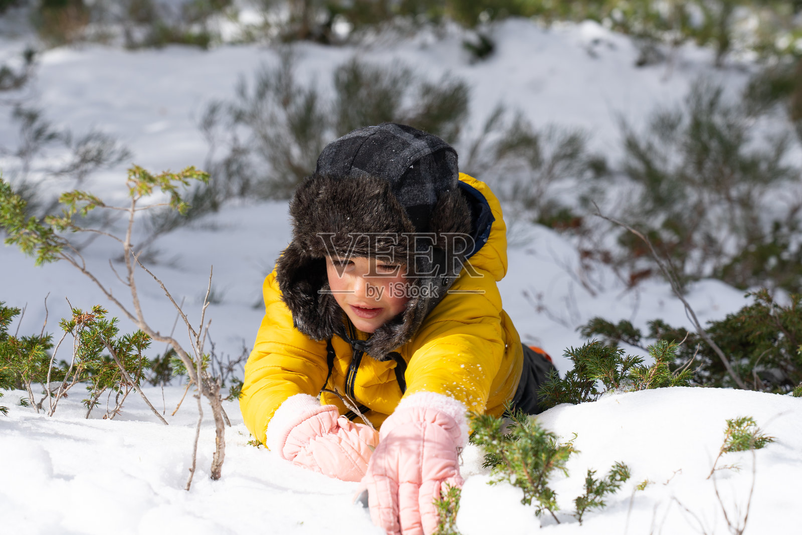 一个白人男孩躺在雪地里玩耍，从近距离看照片摄影图片