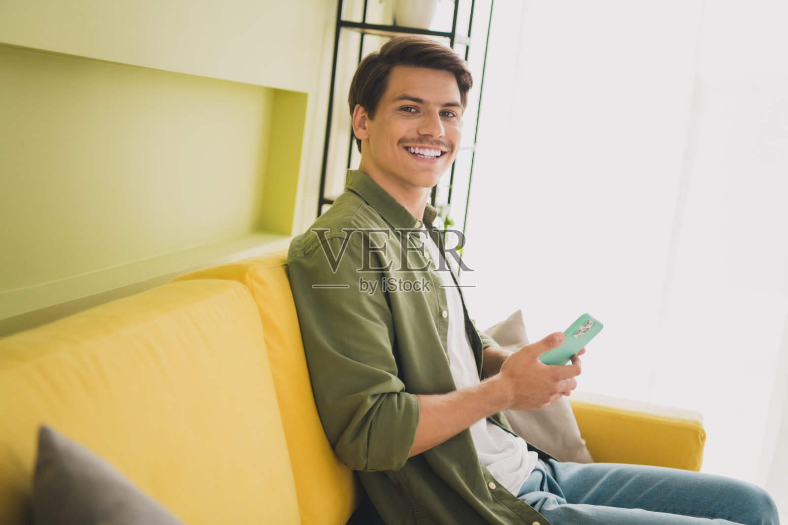 照片正面有魅力的男人穿着时尚的衣服，坐在柔软的沙发现代室内家居室内使用小工具照片摄影图片