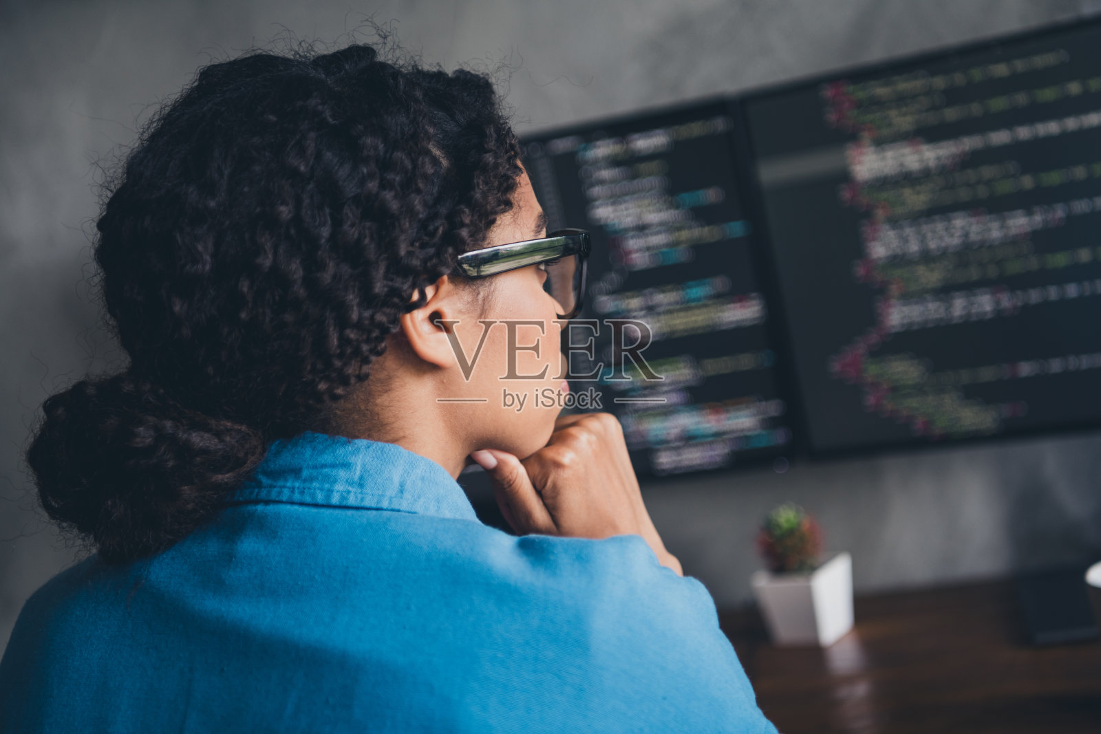 迷人的年轻女子编码的照片看显示器的头脑穿蓝色衬衫现代办公室程序员阁楼房间室内室内工作空间照片摄影图片