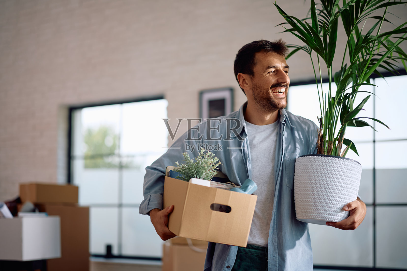 一个快乐的男人搬着自己的东西搬进了新公寓。照片摄影图片