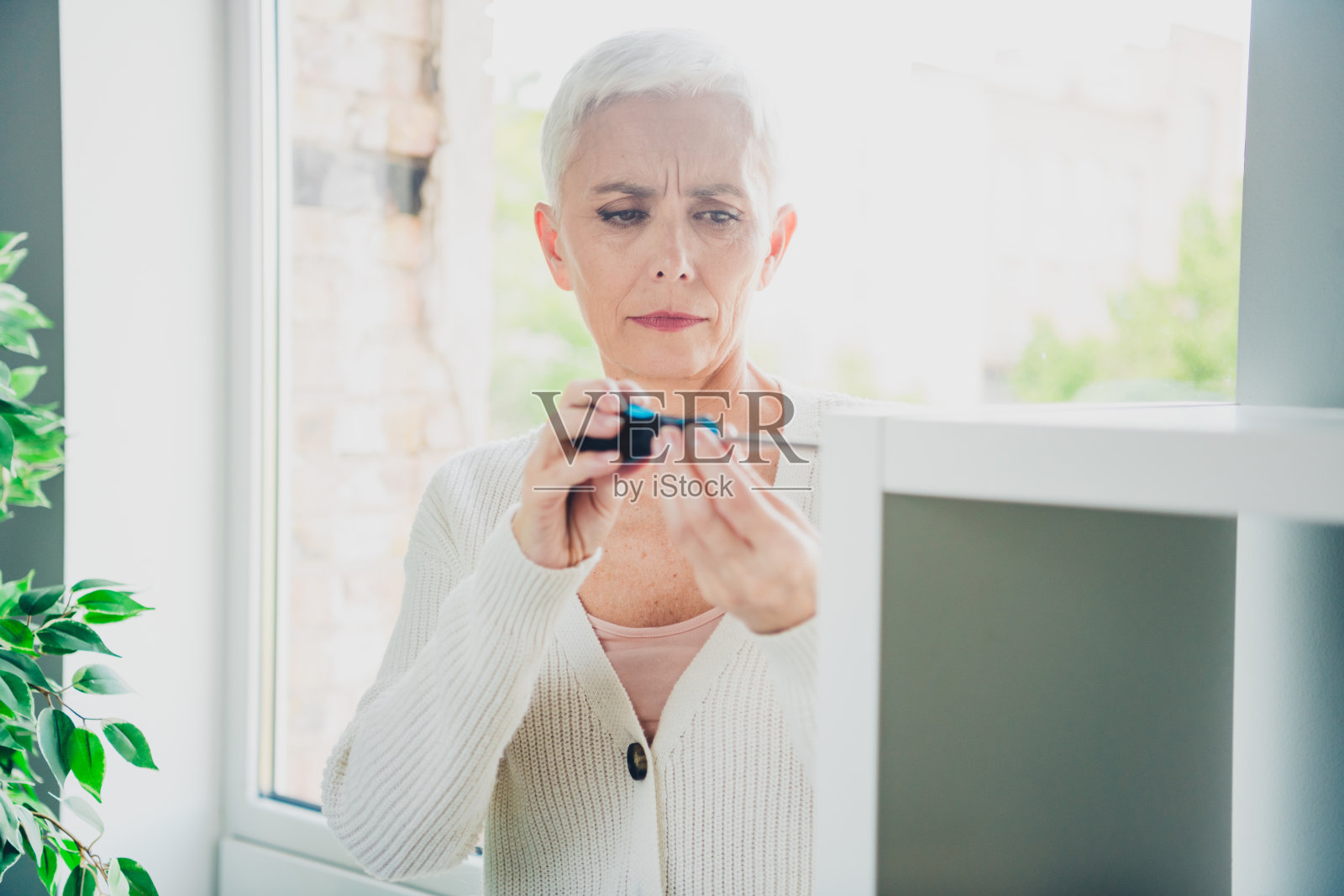 可爱的老年妇女在新公寓的室内修理家具照片摄影图片