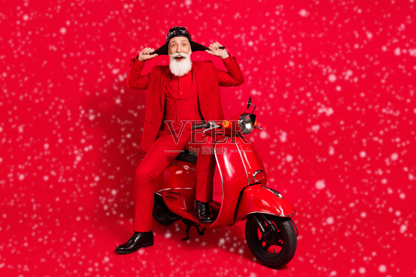 长胡子的男人坐在摩托车上，在蓝绿色的背景上玩得很开心照片摄影图片