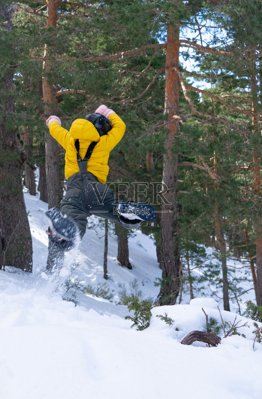 一个无法辨认的男孩在白雪皑皑的森林里跳跃照片摄影图片