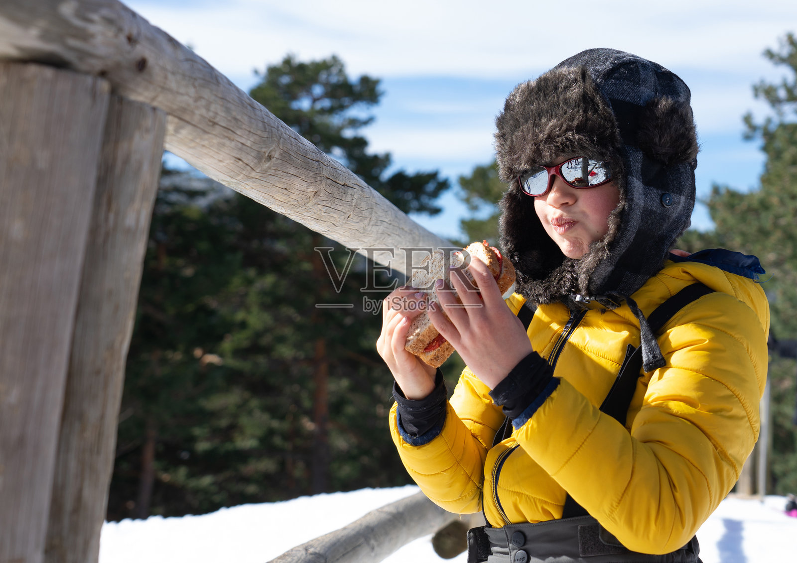 一个白人男孩穿着雪衣在雪地里呆了一天，吃着三明治照片摄影图片