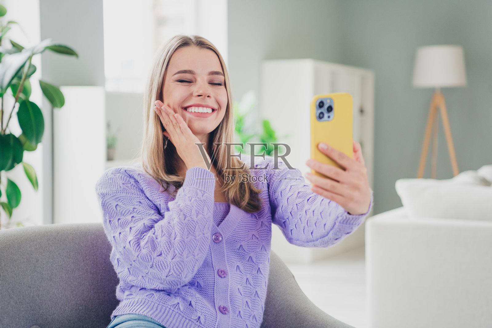 可爱开朗的女孩照片坐在扶手椅可爱的自拍照片穿着紫色的衣服花消遣宽敞的房子室内房间照片摄影图片