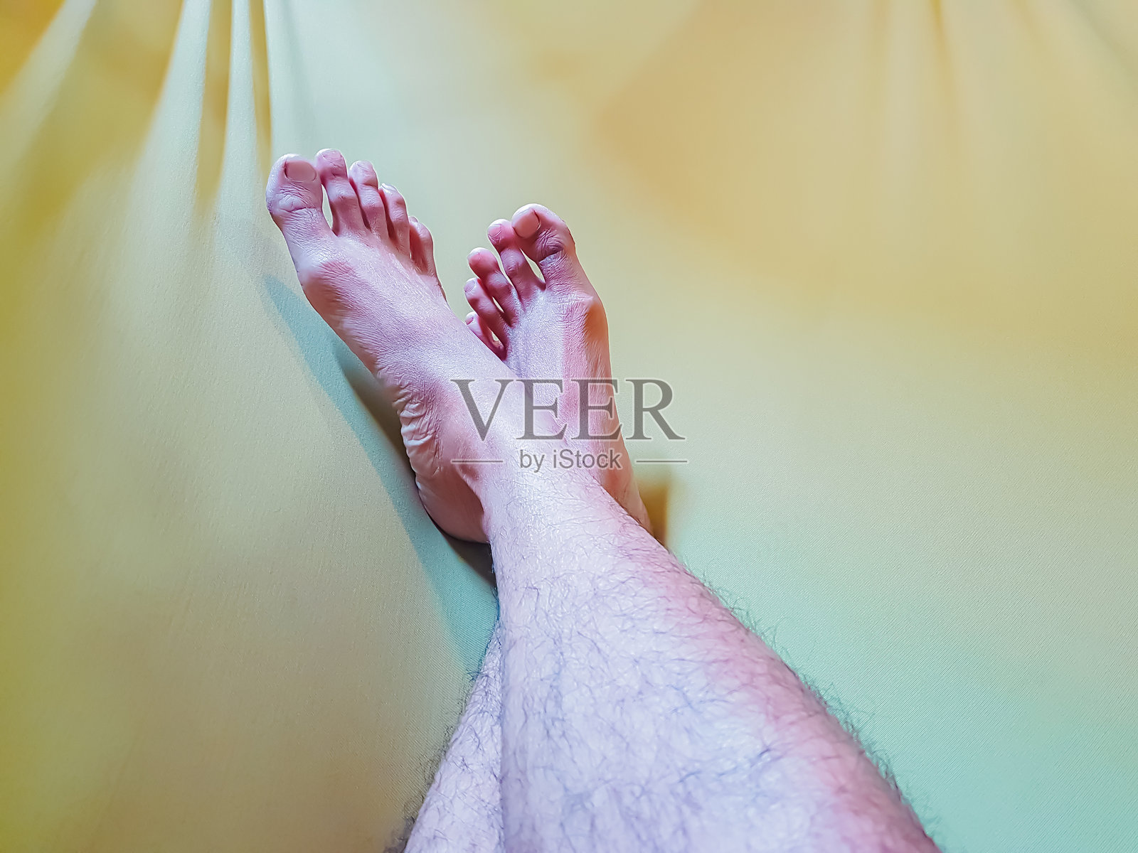 假期休息的男腿，黄色背景上的脚照片摄影图片
