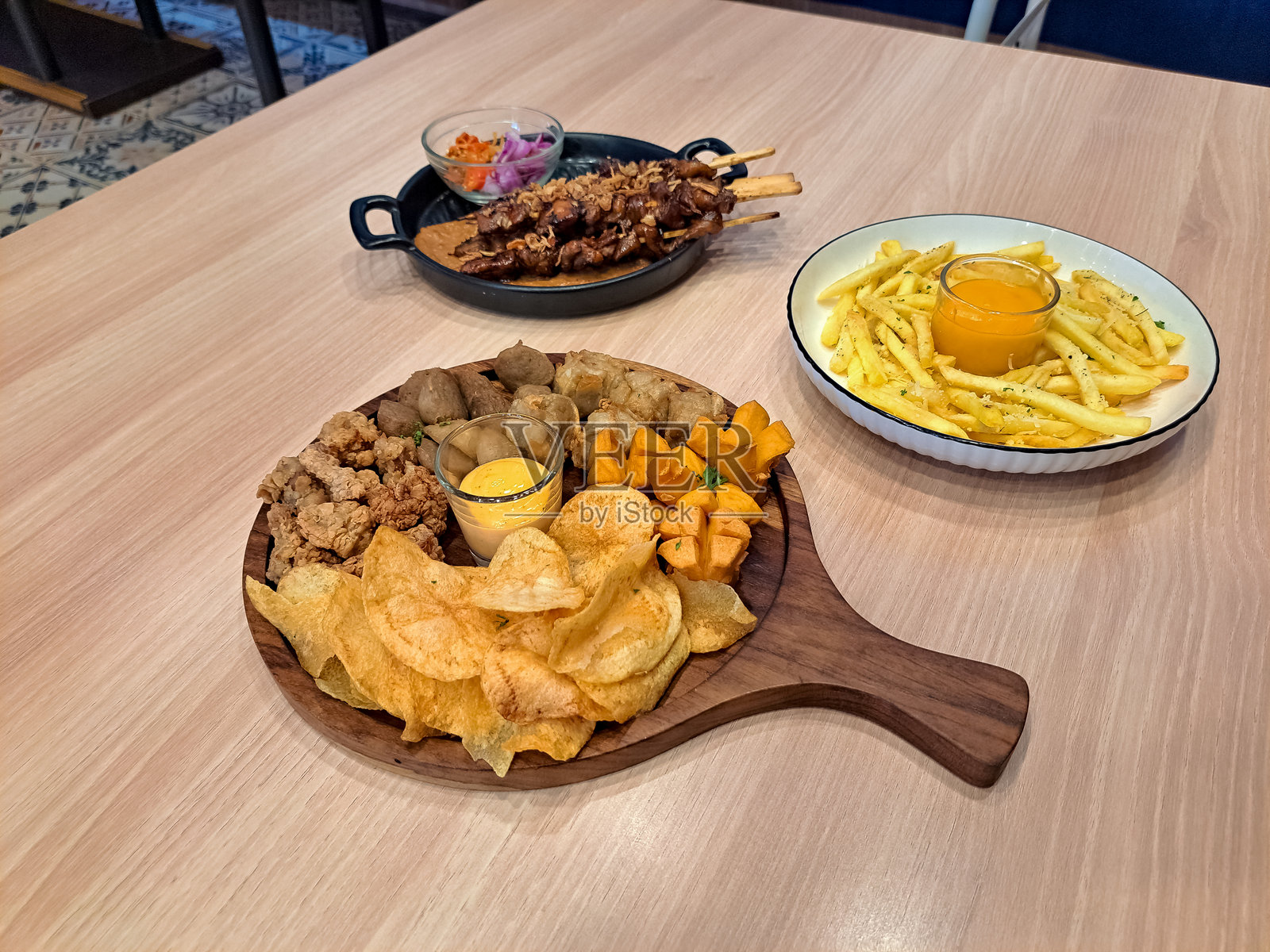 美味的小吃混合拼盘与鸡Karaage，肉丸，鸡Siomay，鸡香肠，薯片和辣蛋黄酱。薯条，奶酪，松露在盘子里。沙爹鸡沙爹配上花生酱和马塔辣椒食品菜单。照片摄影图片