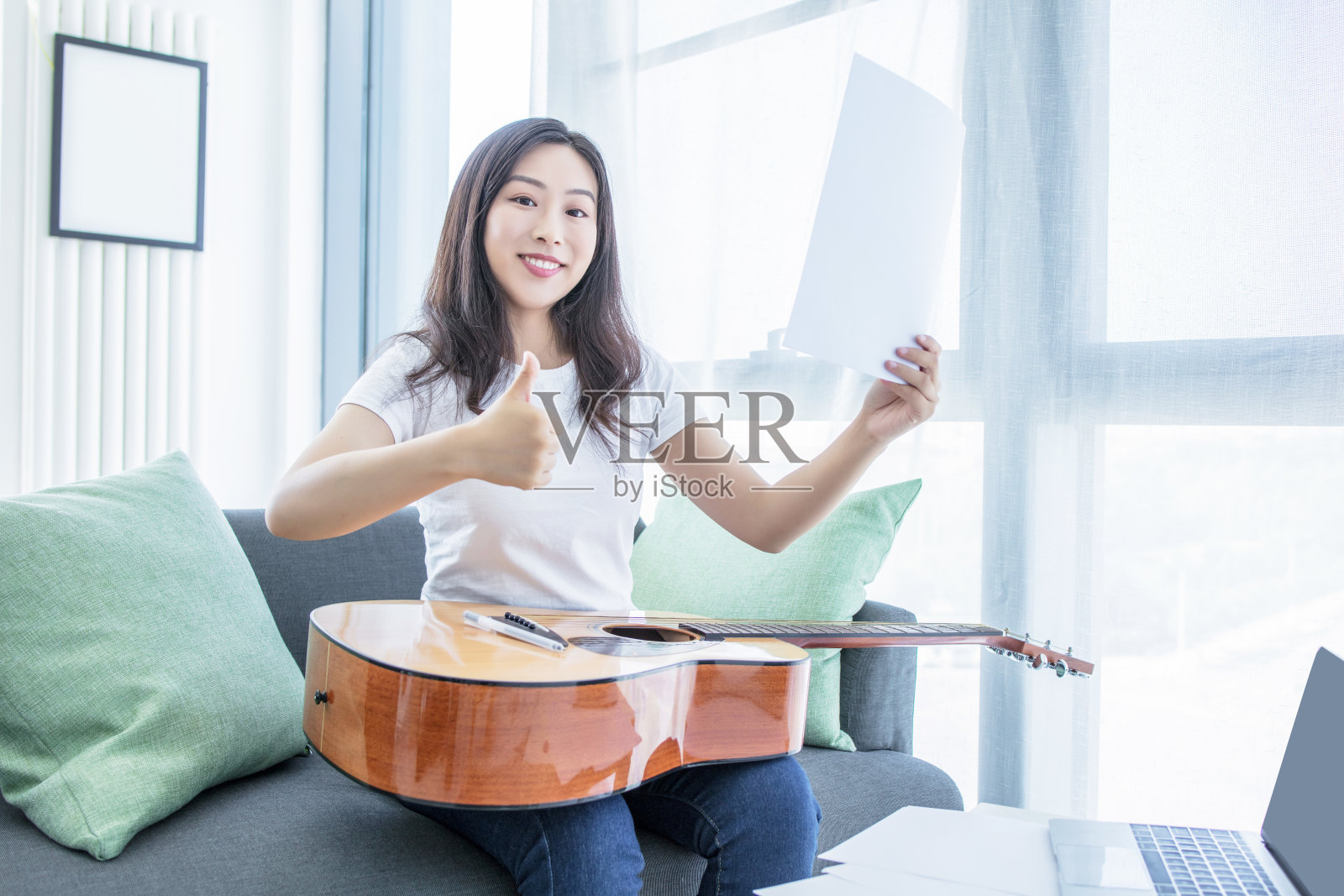 美丽的女人坐在客厅的地板上弹吉他作曲照片摄影图片