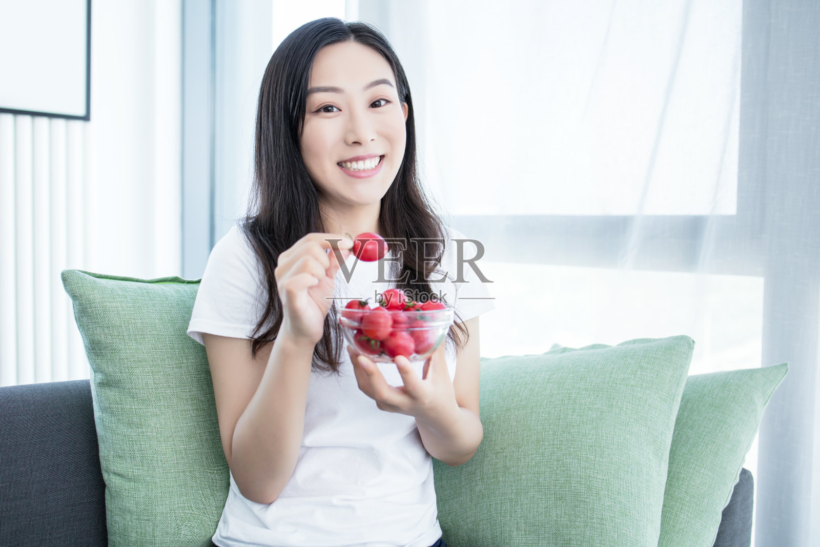 一个女人在室内吃西红柿樱桃沙拉的特写照片摄影图片