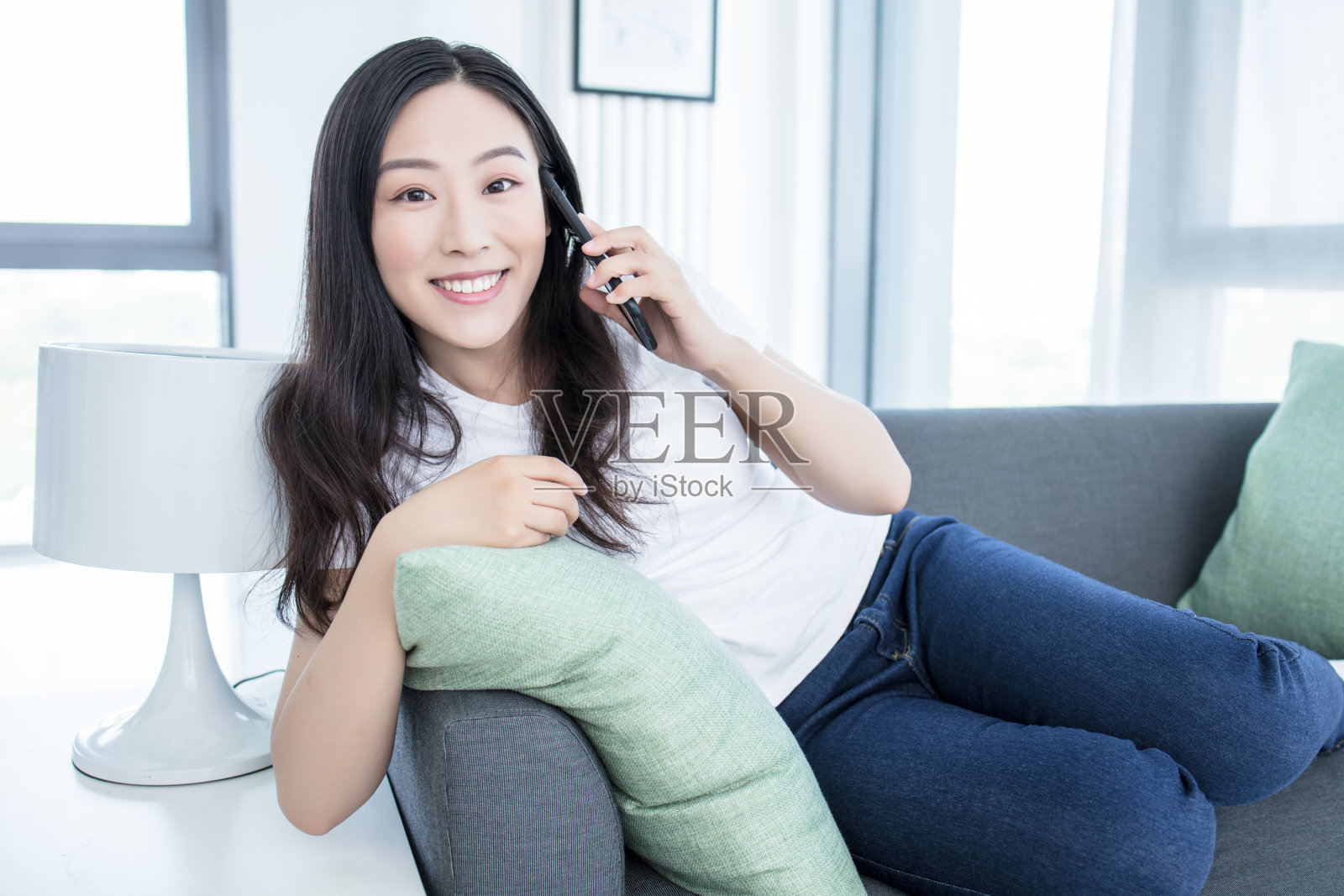 年轻女子在客厅舒适的沙发上使用智能手机照片摄影图片