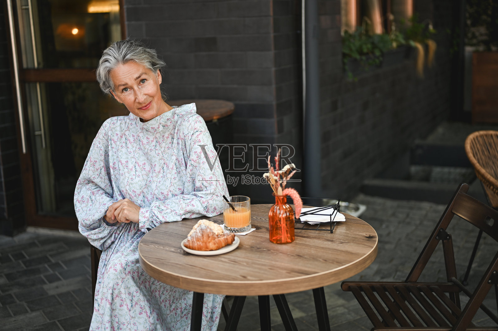 时尚成熟的女人在路边餐厅放松。照片摄影图片