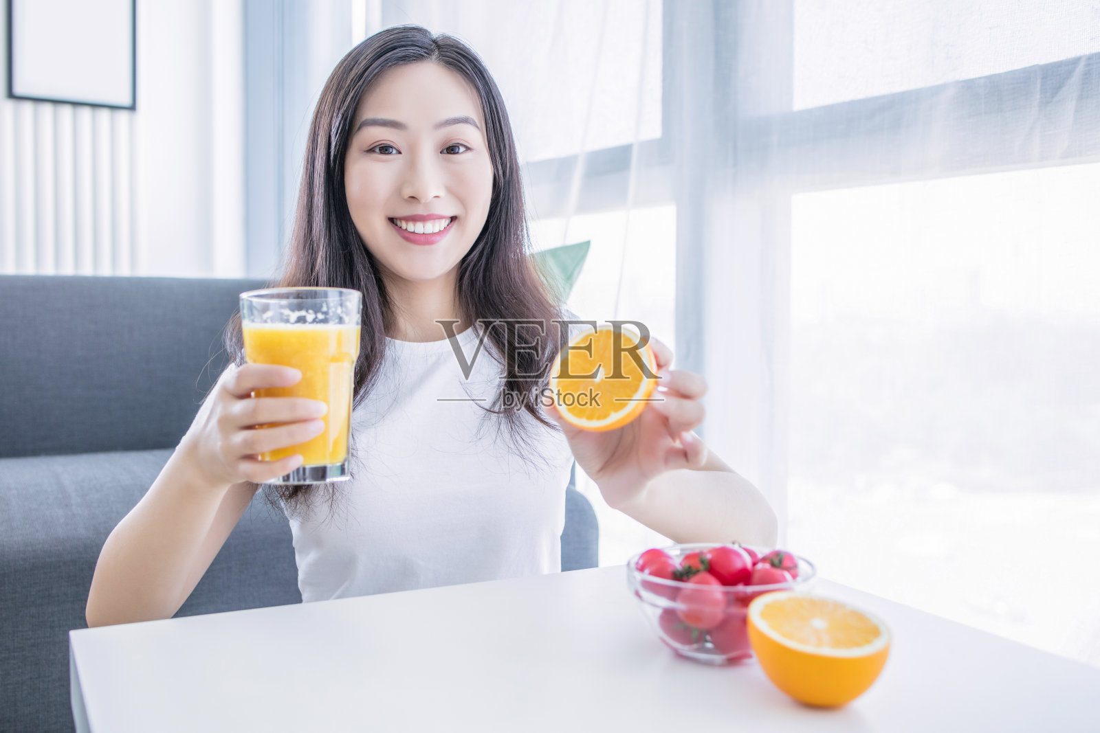 快乐的年轻女子捧着多汁的橙子在她眼前。健康饮食理念。饮食。孤立在白色之上。照片摄影图片