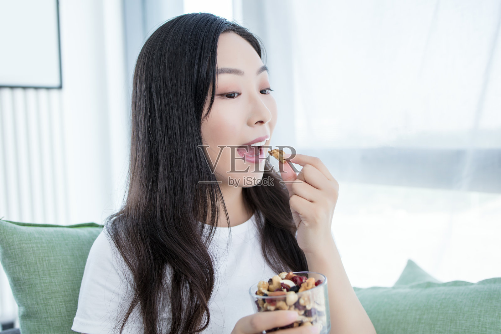 漂亮的年轻女子拿着坚果，开心地微笑着做着ok的手势，拇指向上，非常棒的手势照片摄影图片