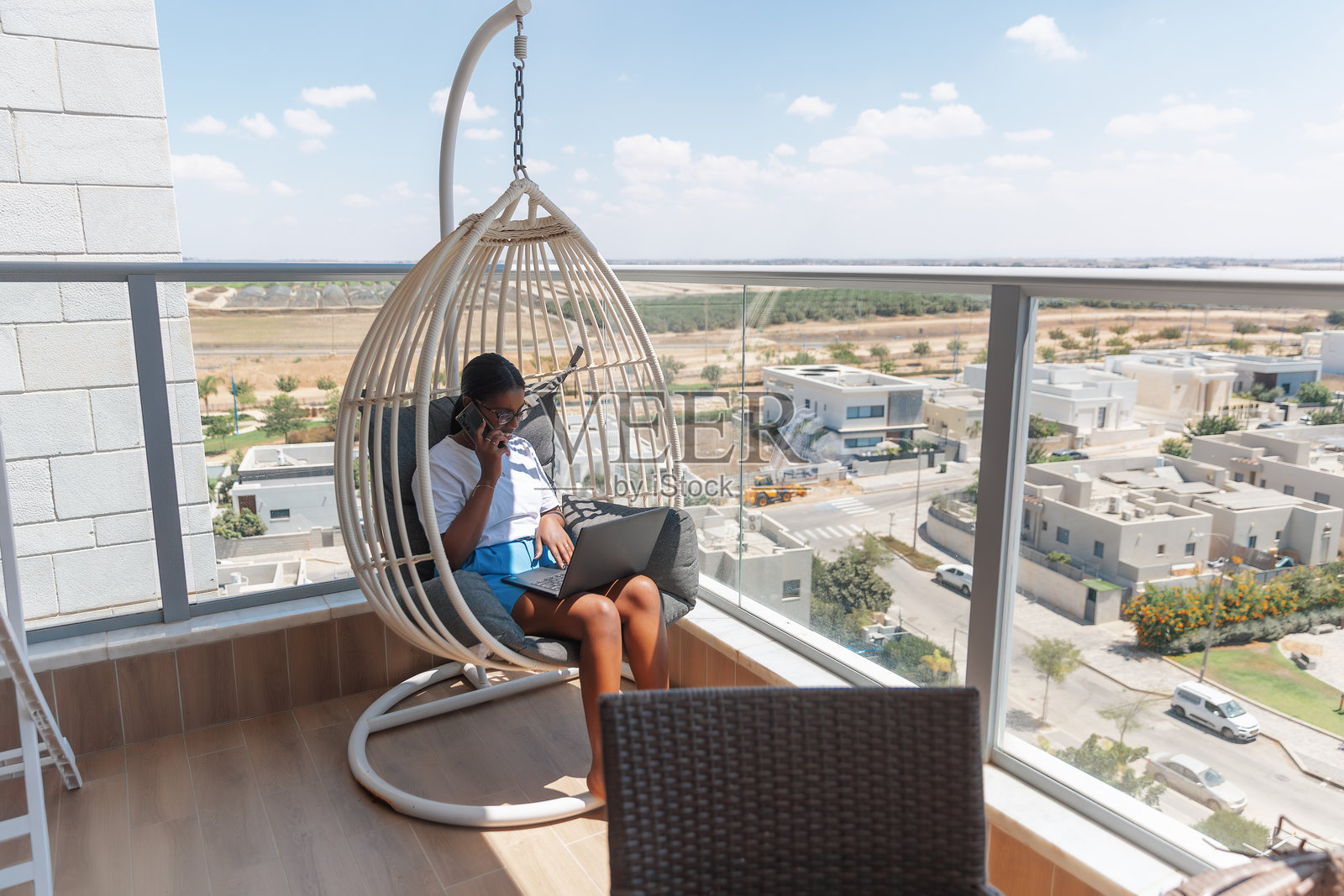 女人在阳台上用手机和笔记本电脑同时处理多项任务照片摄影图片