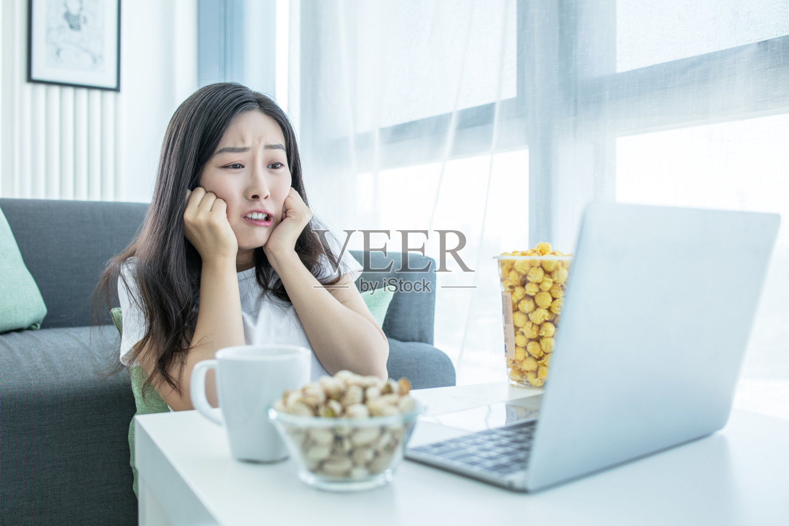 单身女性晚上坐在家里客厅的沙发上看网络电视照片摄影图片