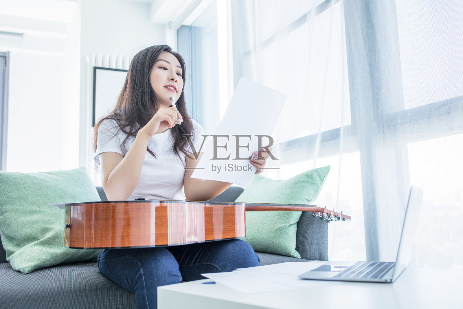 美丽的女人坐在客厅的地板上弹吉他作曲照片摄影图片