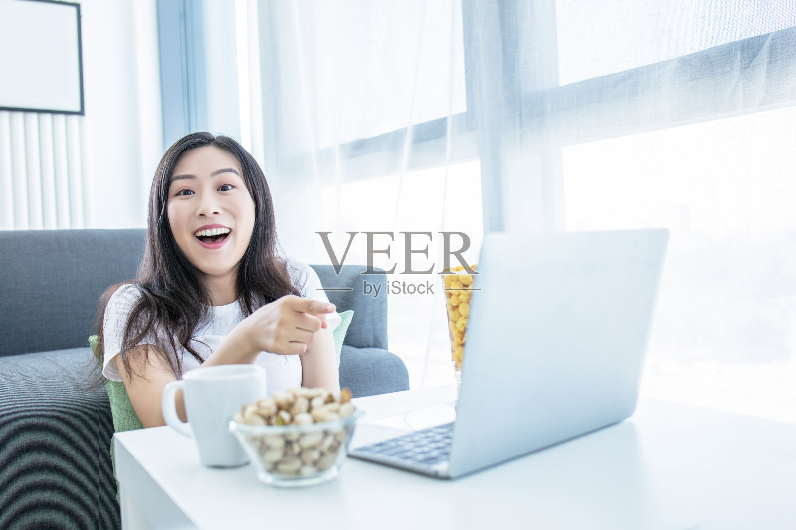 单身女性晚上坐在家里客厅的沙发上看网络电视照片摄影图片