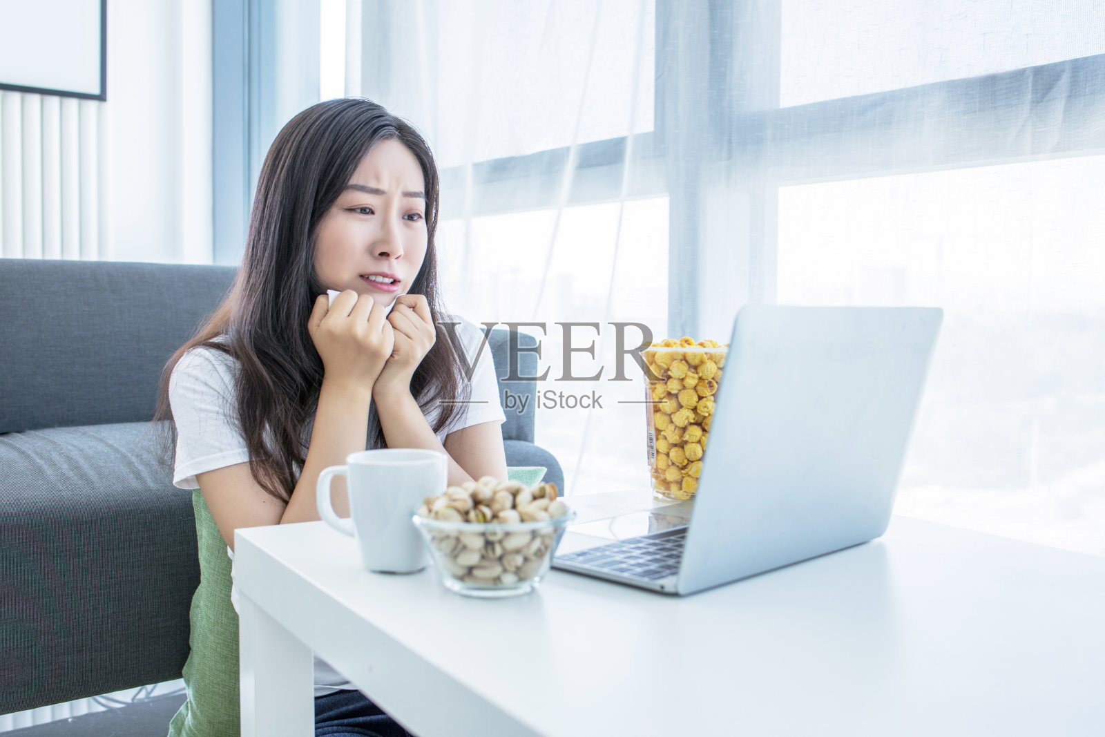 单身女性晚上坐在家里客厅的沙发上看网络电视照片摄影图片