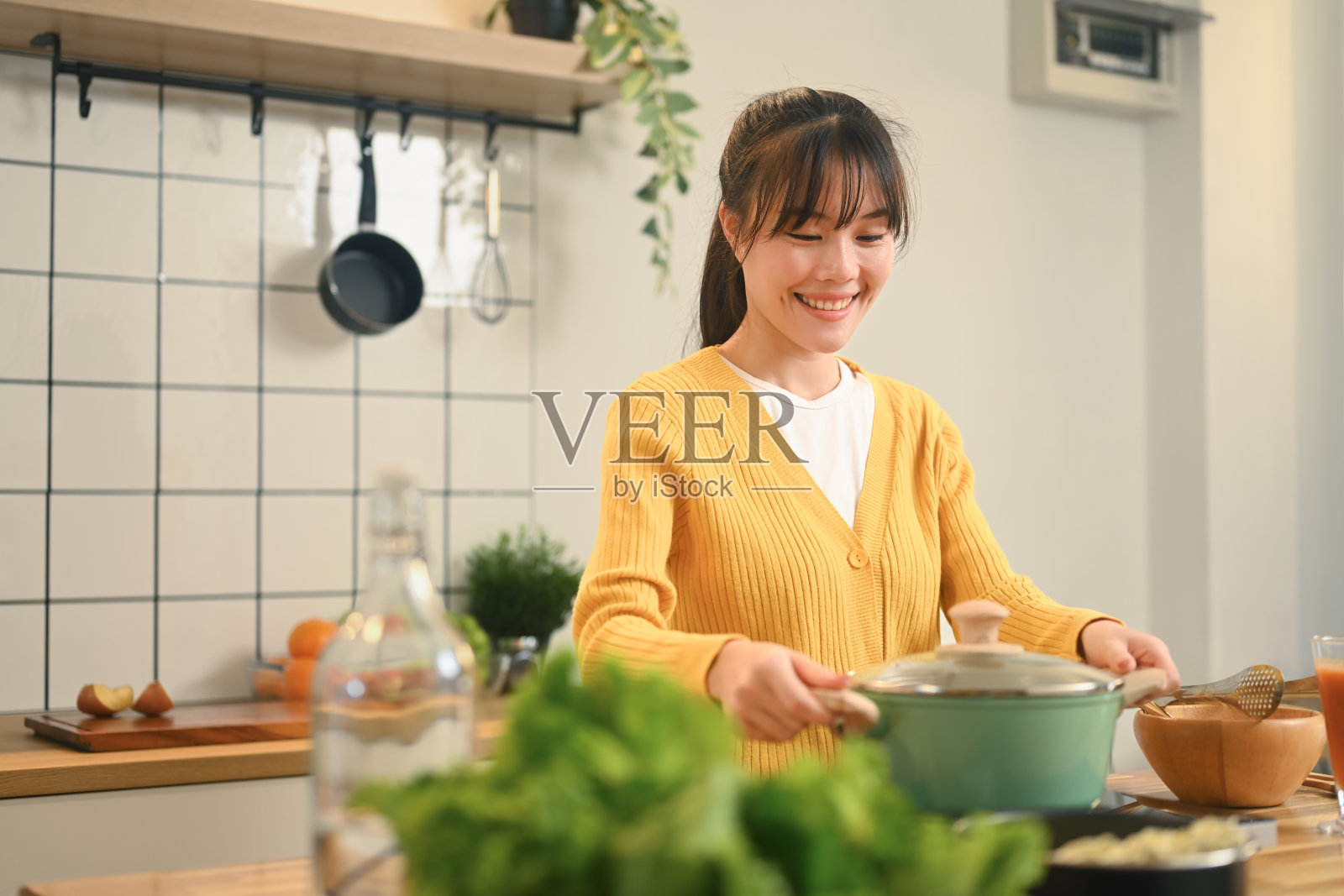 快乐的年轻亚洲女人在现代厨房里准备一顿饭照片摄影图片